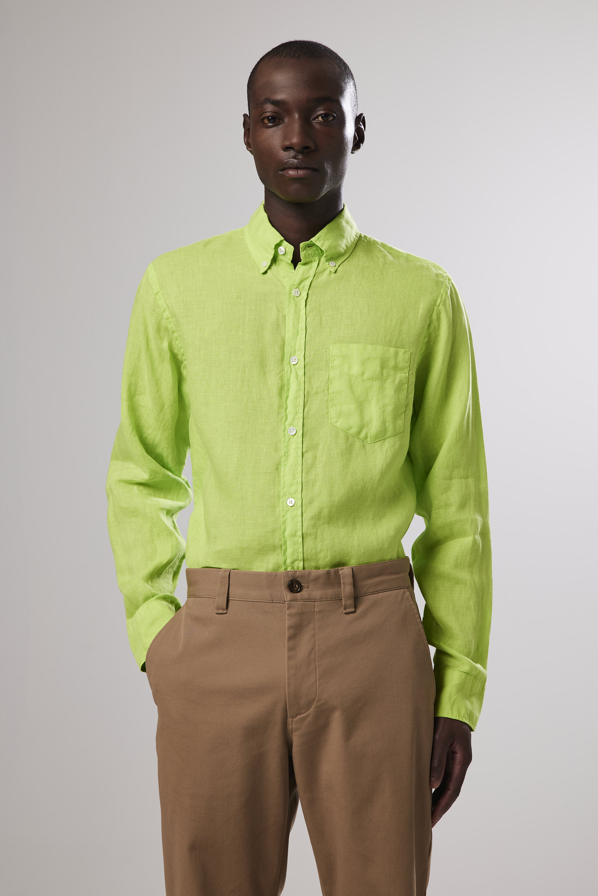 a man holding a bag and wearing khaki pants and a green shirt Stock Photo  by Icons8